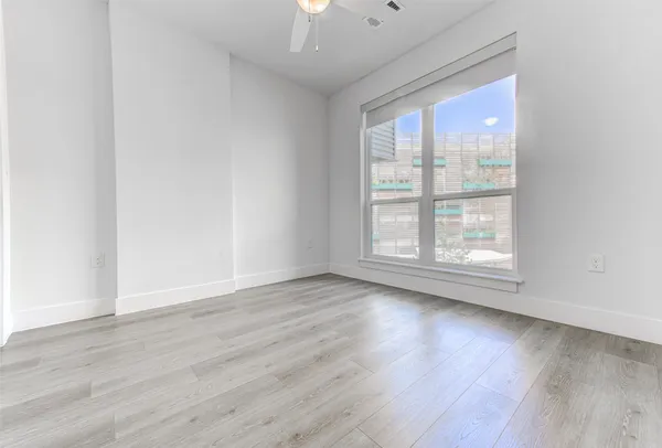 a view of empty room with wooden floor and fan