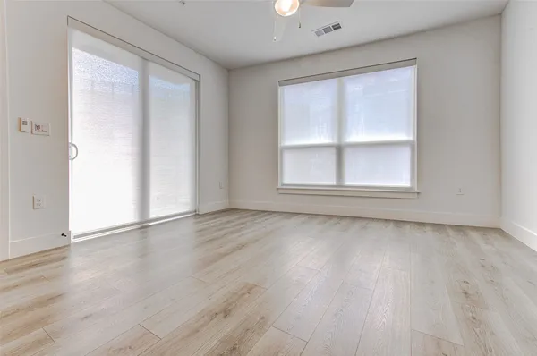 an empty room with wooden floor and windows