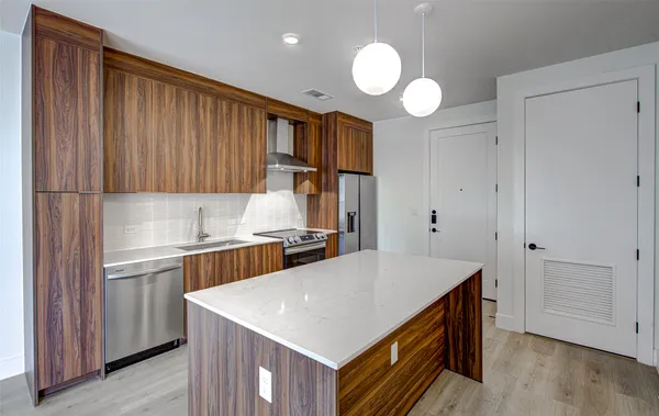 a kitchen with kitchen island granite countertop wooden cabinets a sink and a stove
