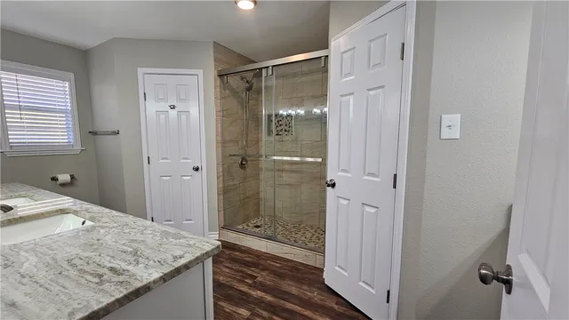 a bathroom with a granite countertop sink a mirror and shower