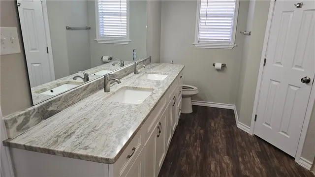 a bathroom with a granite countertop sink a toilet and a vanity