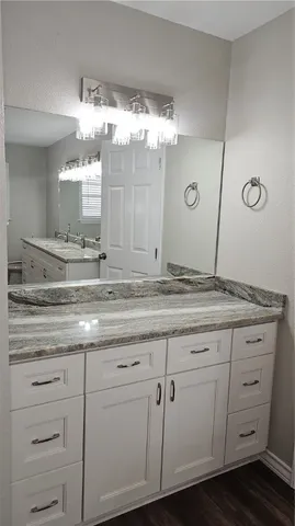 a bathroom with a granite countertop sink mirror and cabinets