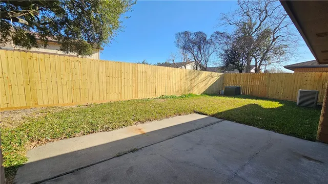 a view of backyard with large tree and wooden fence