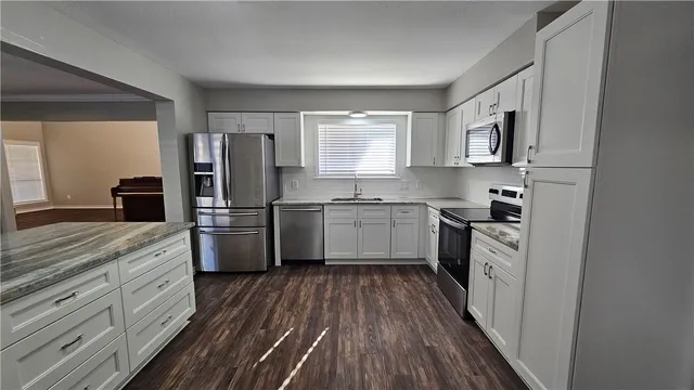 a kitchen with a sink cabinets stainless steel appliances and a window