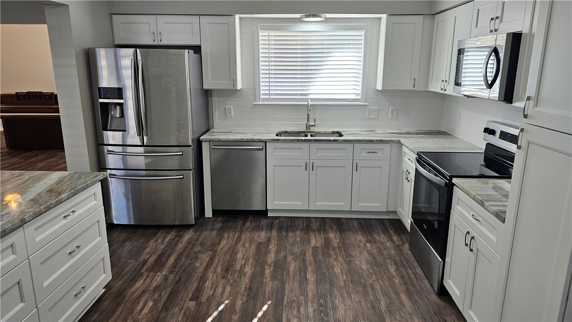 2438 Scotch Moss Drive Corpus Christi, TX 78414 - Photo 7 of 34 a kitchen with white cabinets stainless steel appliances a sink and a window