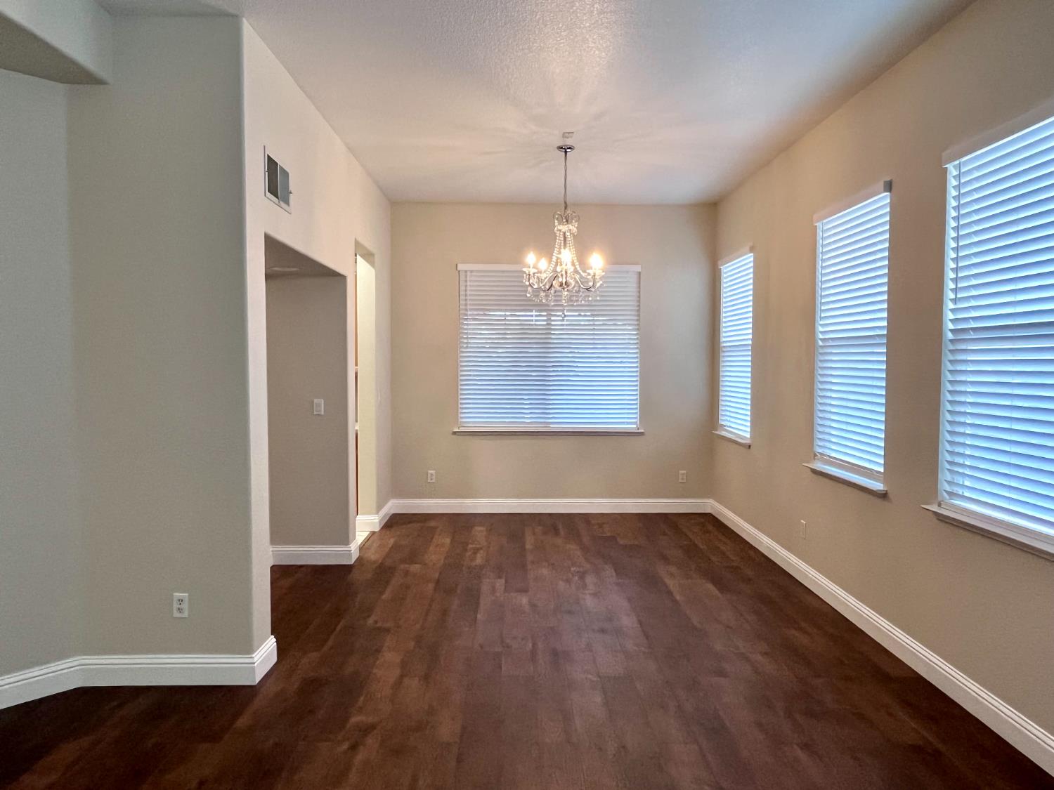 13310 Parkhaven Street Lathrop, CA 95330 - Photo 5 of 27 an empty room with wooden floor chandelier and windows