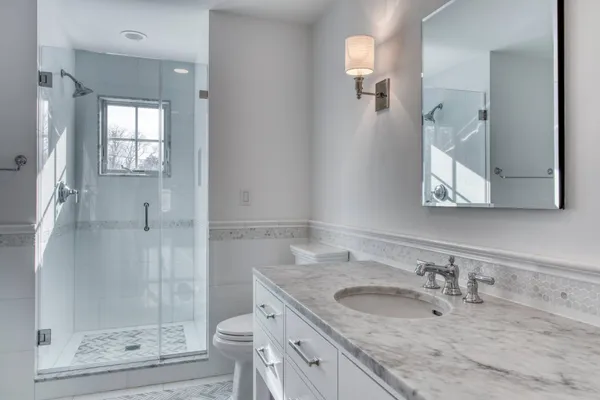 a bathroom with a granite countertop sink a mirror and shower