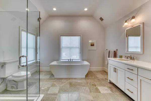 a spacious bathroom with a double vanity sink toilet mirror and bathtub