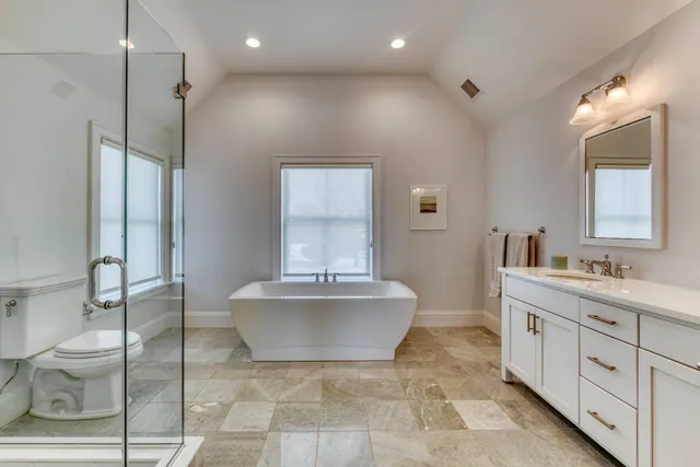 a spacious bathroom with a double vanity sink toilet mirror and bathtub