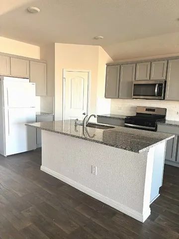 a kitchen with stainless steel appliances granite countertop a sink a stove a refrigerator a microwave oven with white cabinets and wooden floor