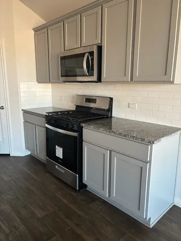 a kitchen with granite countertop wooden cabinets and a stove top oven