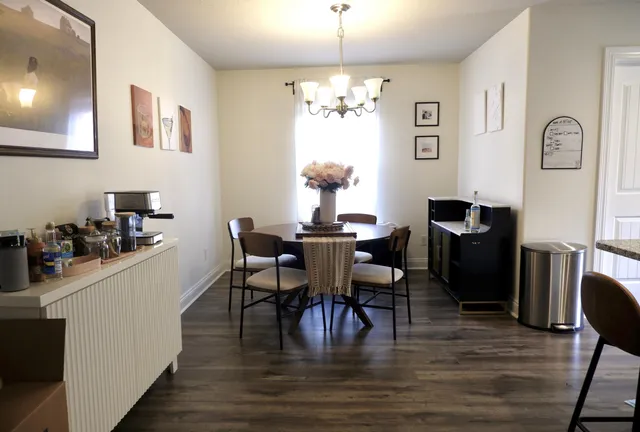 a dining room with wooden floor a chandelier a wooden table and chairs