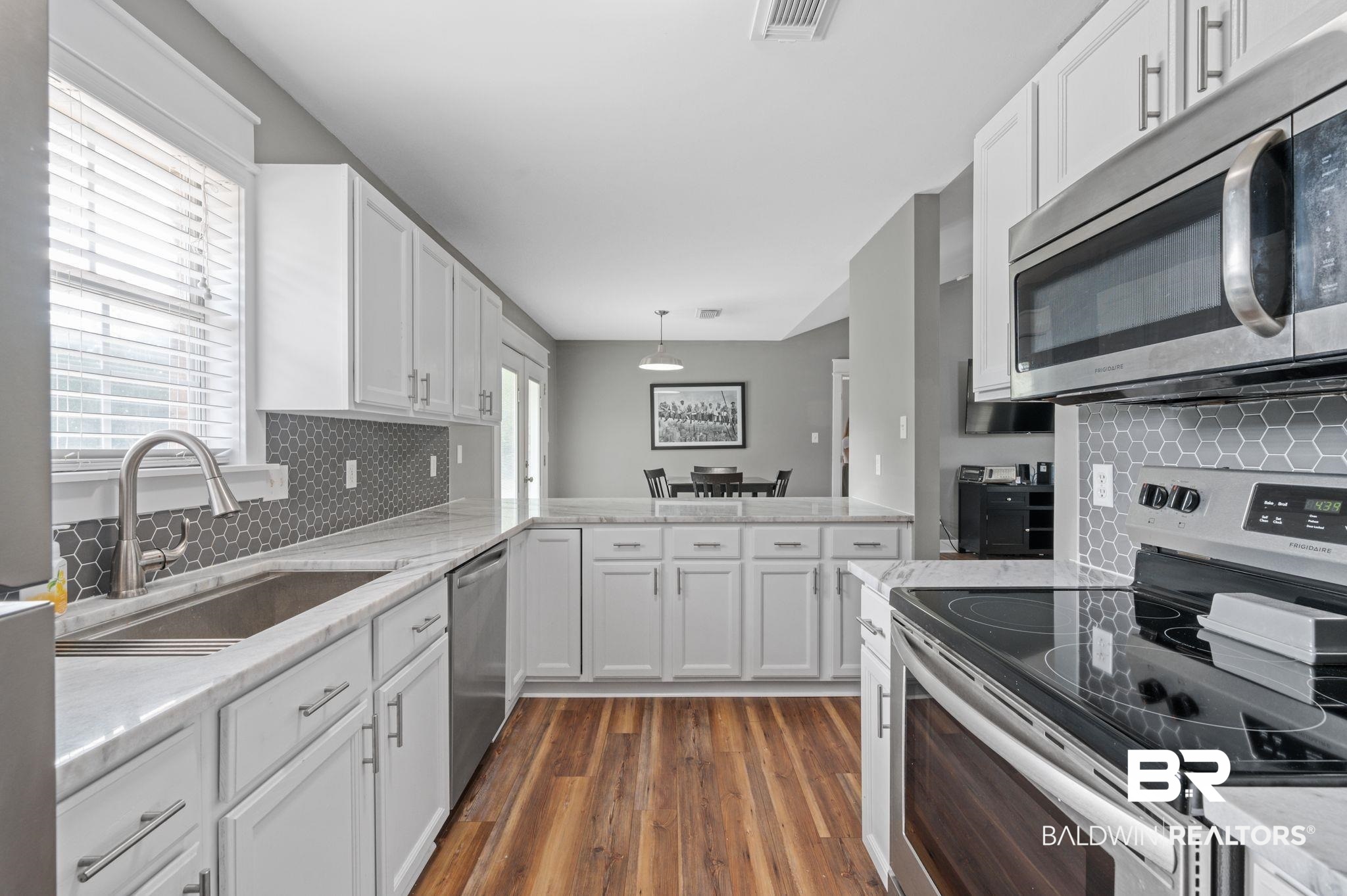 1107 North Oak Street Loxley, AL 36551 - Photo 10 of 40 Kitchen with dark hardwood / wood-style flooring, backsplash, appliances with stainless steel finishes, kitchen peninsula, and sink