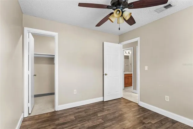 a view of an empty room and window with a chandelier fan
