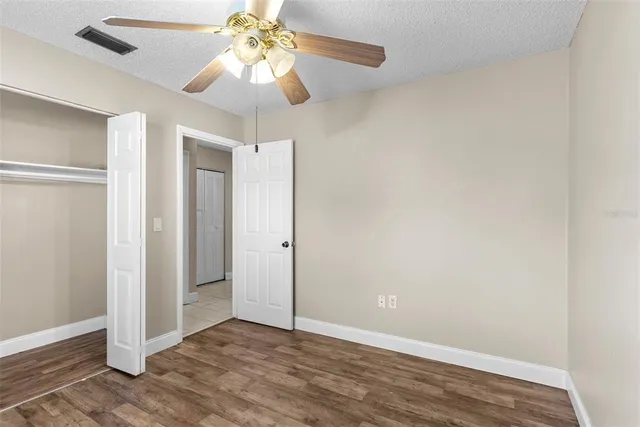 an empty room with wooden floor closet and windows