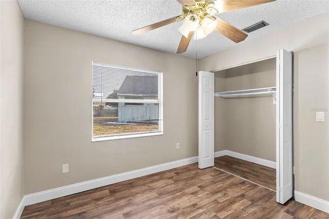 a view of an empty room with window and wooden floor