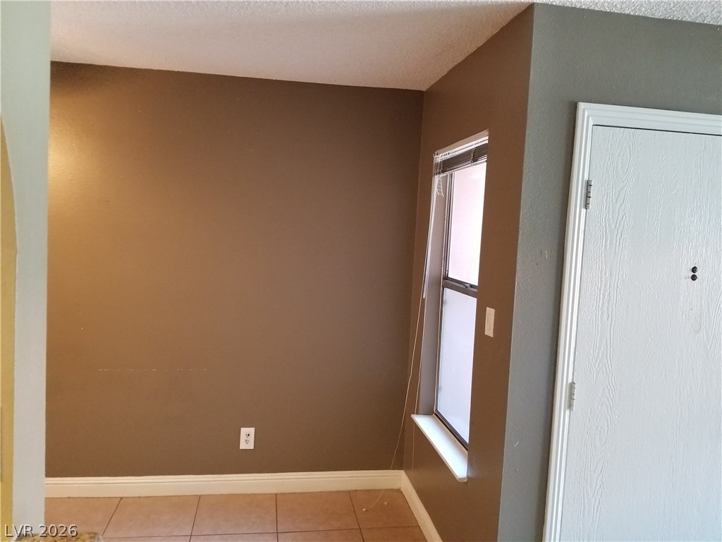 1515 East Reno Avenue, Unit A103 Las Vegas, NV 89119 - Photo 9 of 16 This living space features tiled flooring and a bright window, offering a pleasant and functional interior.