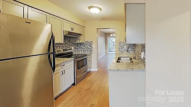 a kitchen with stainless steel appliances granite countertop a refrigerator and a stove