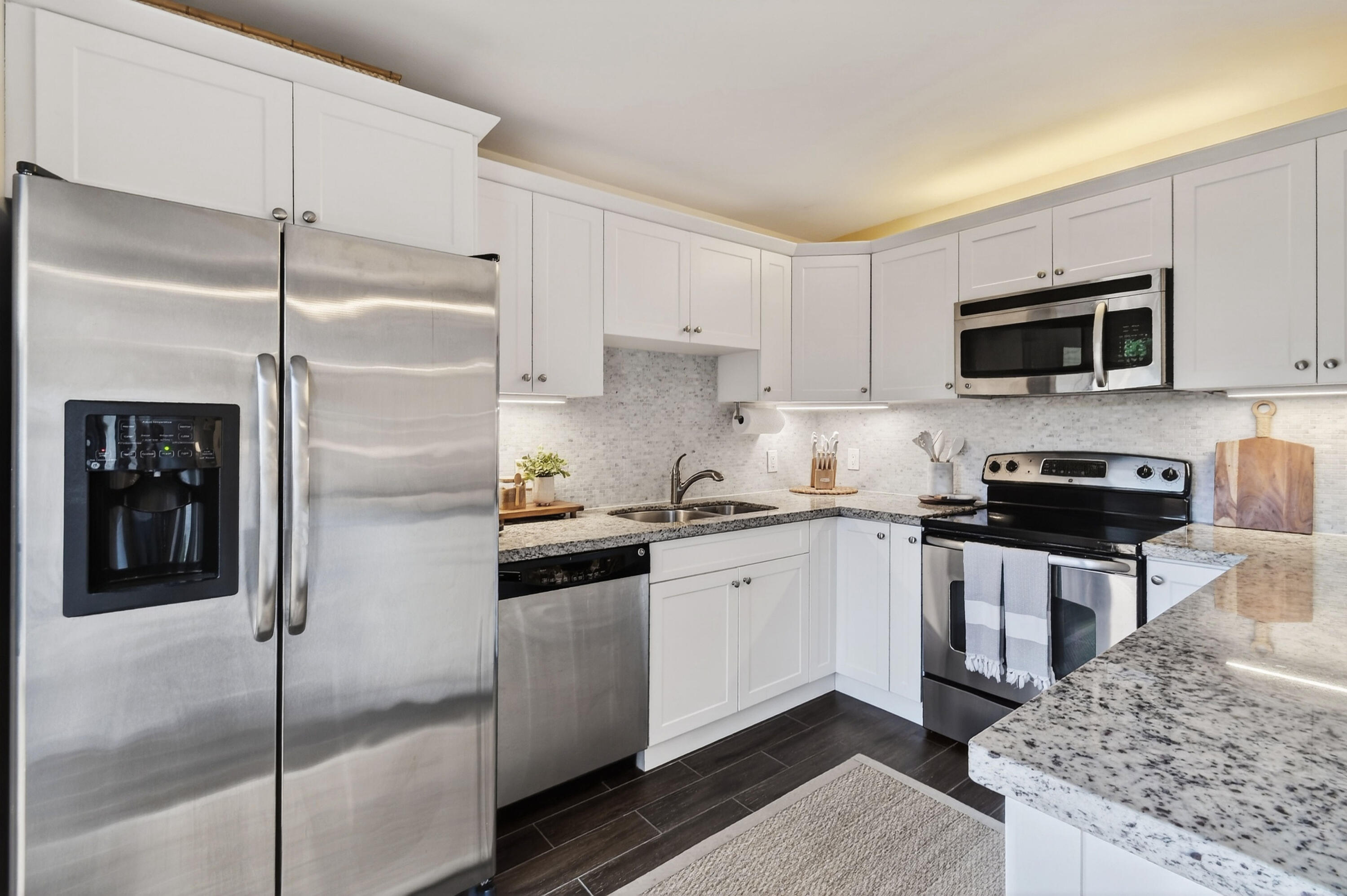3900 County Line Road, Unit 15A Tequesta, FL 33469 - Photo 13 of 37 a kitchen with stainless steel appliances granite countertop a refrigerator a stove and a sink with wooden floor