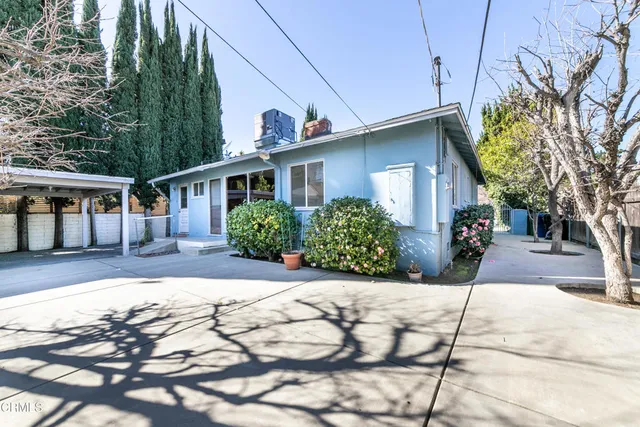 a front view of a house with a yard and potted plants