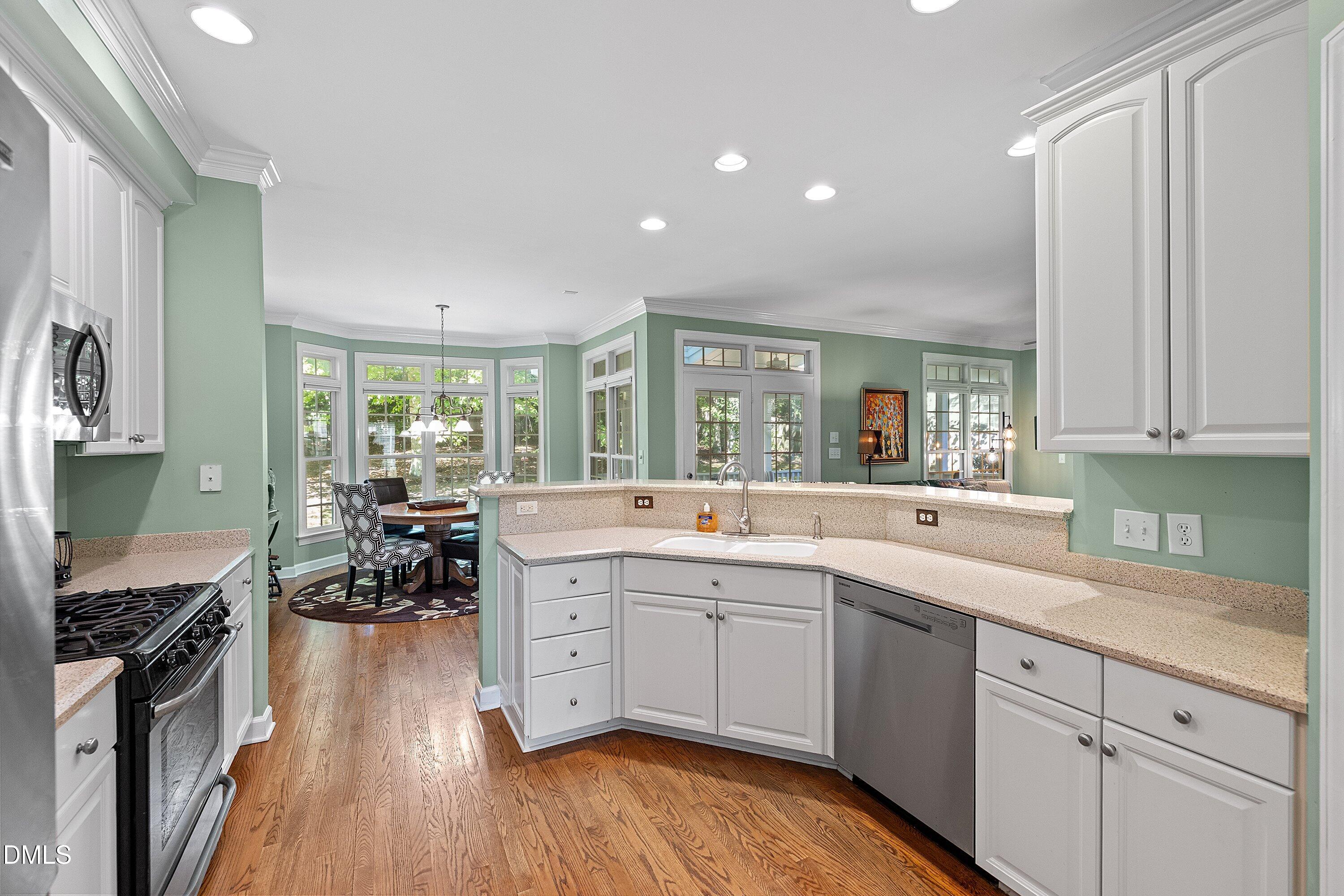 3914 Sterling Ridge Lane Durham, NC 27707 - Photo 24 of 66 Kitchen featuring wood-finish flooring, white cabinetry, integrated stainless steel appliances, and a pass-through counter