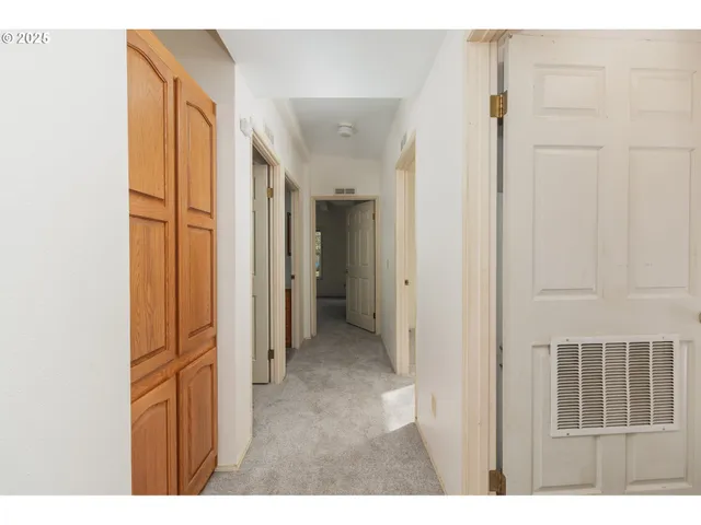 a view of a hallway to a bedroom with wooden floor and windows