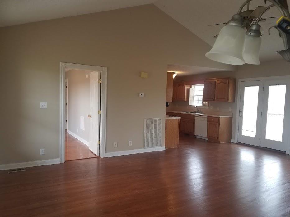 4686 Matthews Road Cedar Hill, TN 37032 - Photo 5 of 20 an empty room with wooden floor and a kitchen