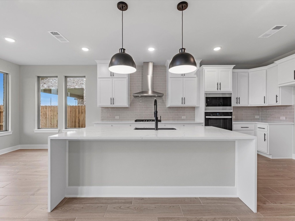 213 Buckaroo Drive Georgetown, TX 78633 - Photo 5 of 22 a kitchen with stainless steel appliances granite countertop a sink a stove and a wooden floor
