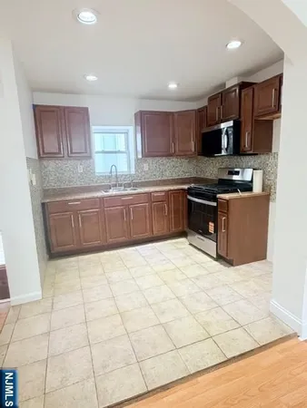 a large kitchen with stainless steel appliances granite countertop a stove top oven a sink a counter top space and cabinets