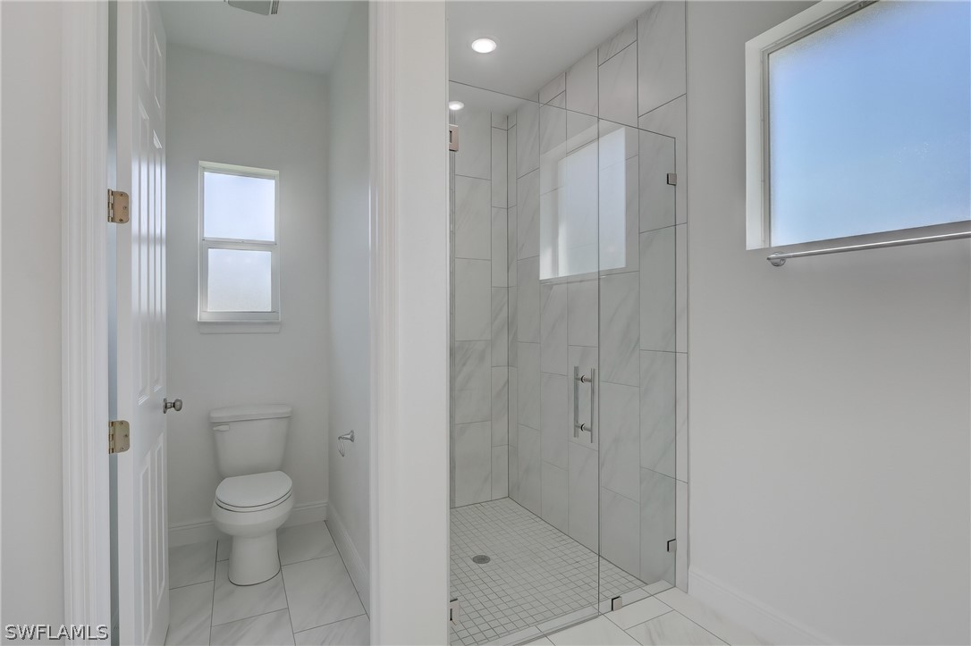 18457 Lee Road Fort Myers, FL 33967 - Photo 16 of 28 a bathroom with a granite countertop toilet a sink and shower