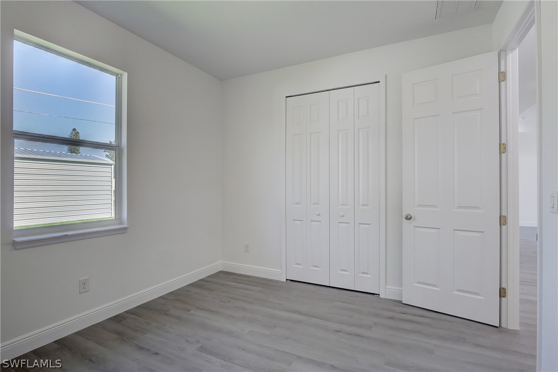 18457 Lee Road Fort Myers, FL 33967 - Photo 22 of 28 a view of an empty room with wooden floor and a window