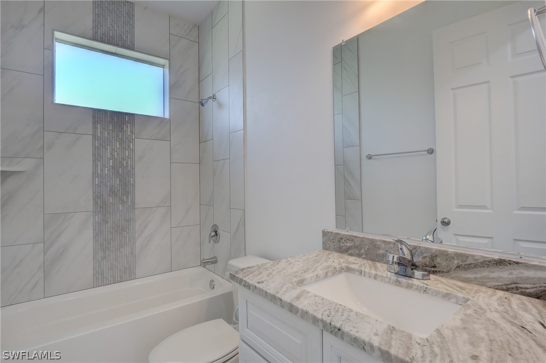 18457 Lee Road Fort Myers, FL 33967 - Photo 23 of 28 a bathroom with a granite countertop sink a toilet and bathtub