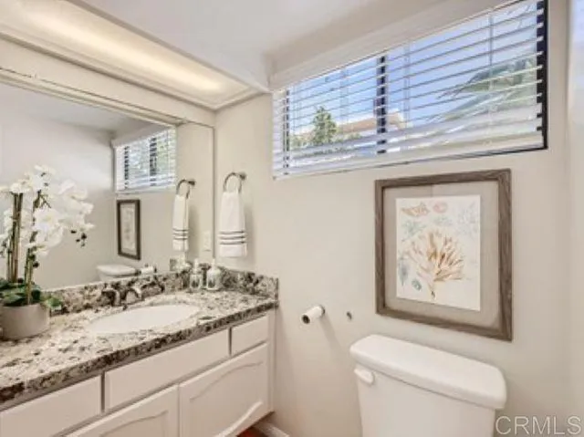 a bathroom with a granite countertop sink a toilet and a mirror