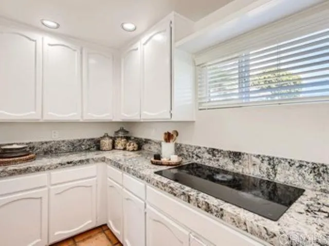 a kitchen with granite countertop white cabinets and white appliances