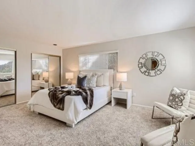 a spacious bedroom with a bed a mirror and a large window