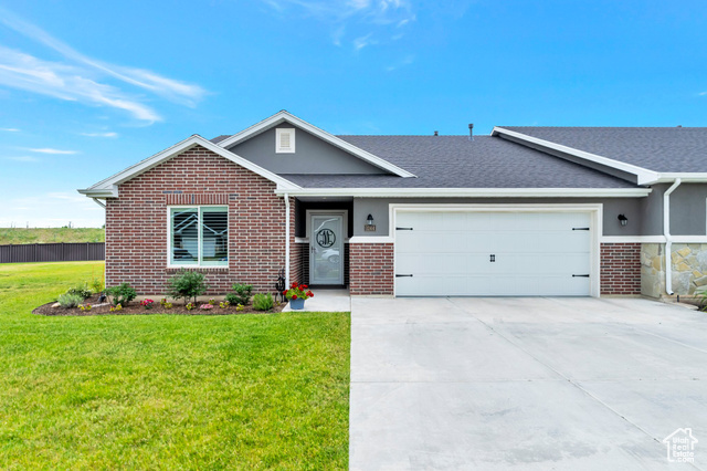 Ranch-style home featuring a front lawn and a garage