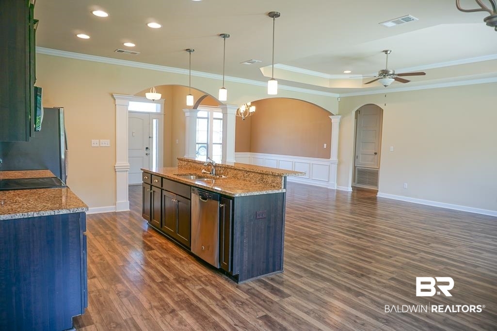 593 Begeman Road Mobile, AL 36608 - Photo 5 of 23 Kitchen featuring light stone counters, dark hardwood / wood-style floors, a center island with sink, stainless steel dishwasher, and sink