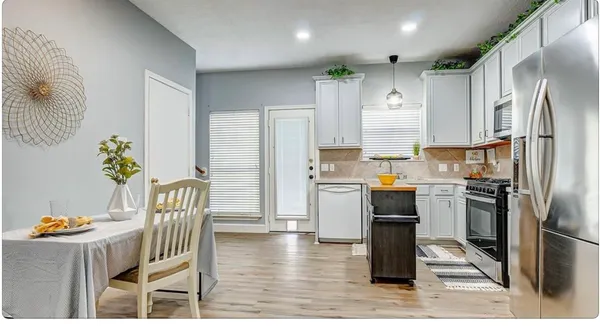 a kitchen with granite countertop a refrigerator a stove a sink a dining table and chairs