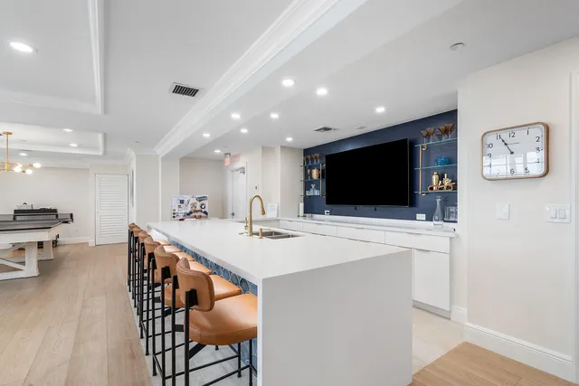 a kitchen with stainless steel appliances a stove a refrigerator a microwave oven a dining table and chairs with wooden floor