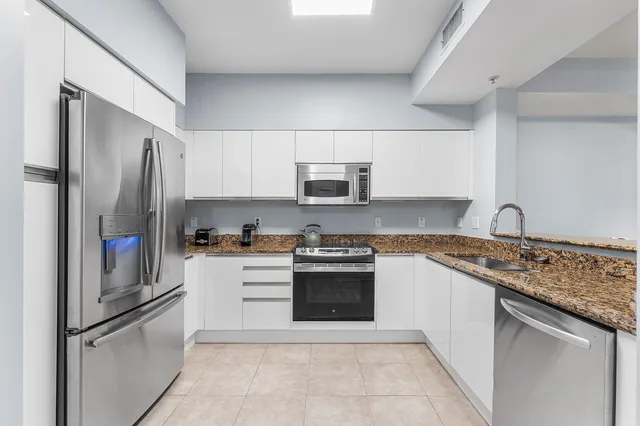 a kitchen with stainless steel appliances granite countertop a refrigerator sink and stove