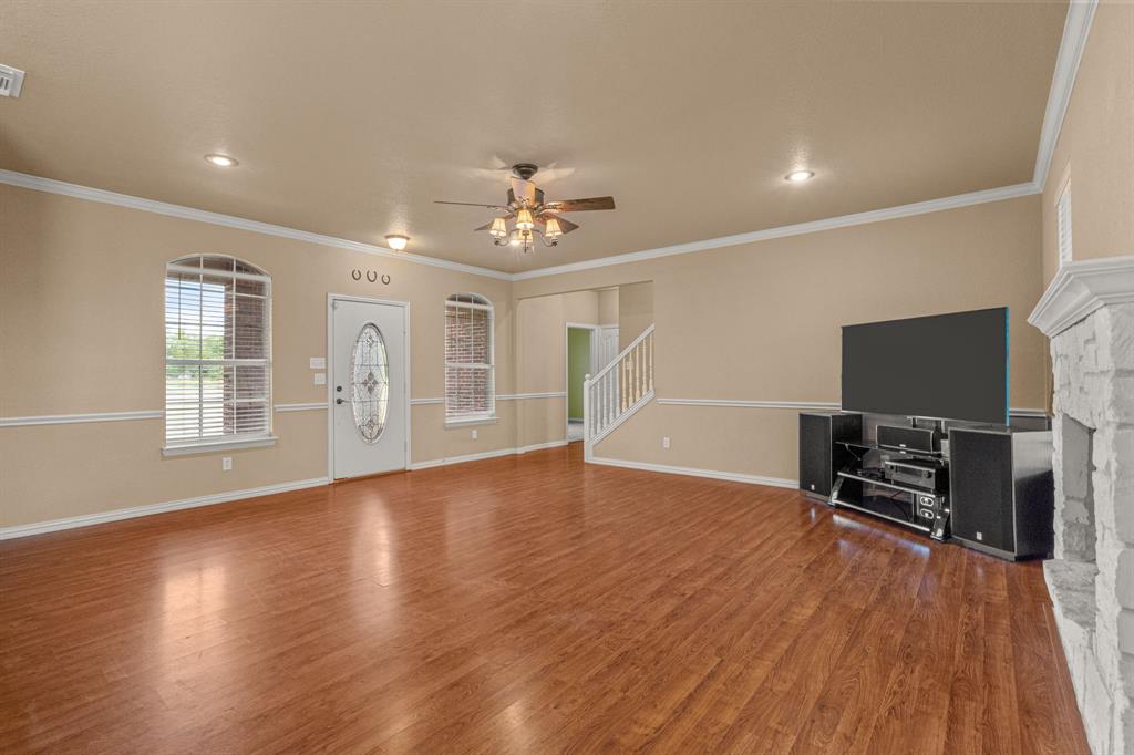 6501 Indian Trail Sanger, TX 76266 - Photo 3 of 39 Unfurnished living room featuring ceiling fan, wood finished floors, ornamental molding, and a fireplace