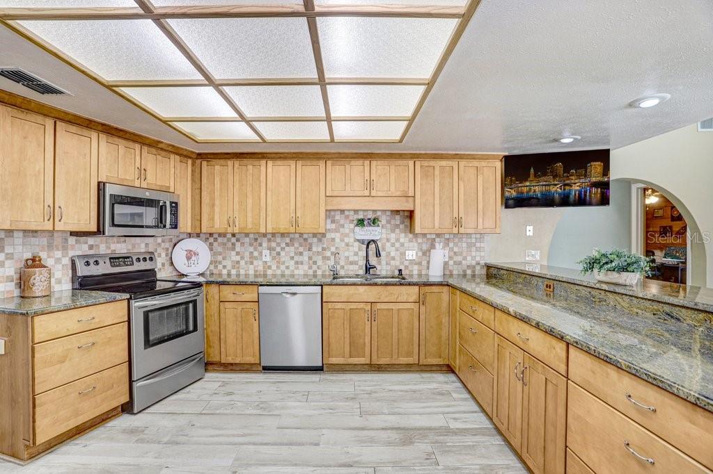 504 Triple Crown Court Seffner, FL 33584 - Photo 5 of 63 a kitchen with stainless steel appliances granite countertop wooden cabinets a sink a stove a refrigerator and dishwasher with wooden floor