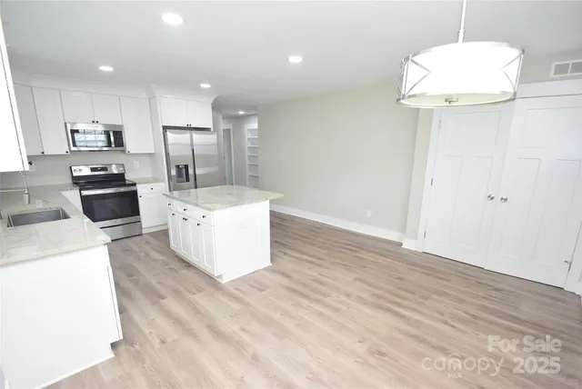 a large white kitchen with a refrigerator a stove top oven a sink and dishwasher