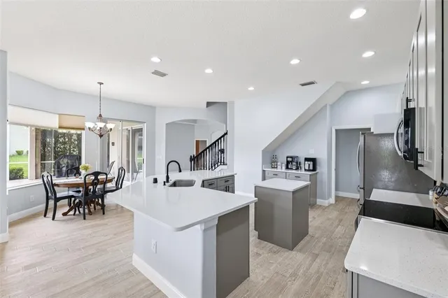 a kitchen with stainless steel appliances kitchen island a stove a refrigerator a dining table and chairs with wooden floor