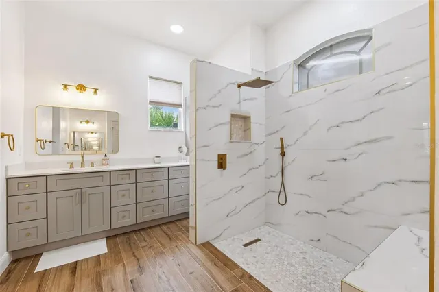 a spacious bathroom with a granite countertop sink a mirror and shower