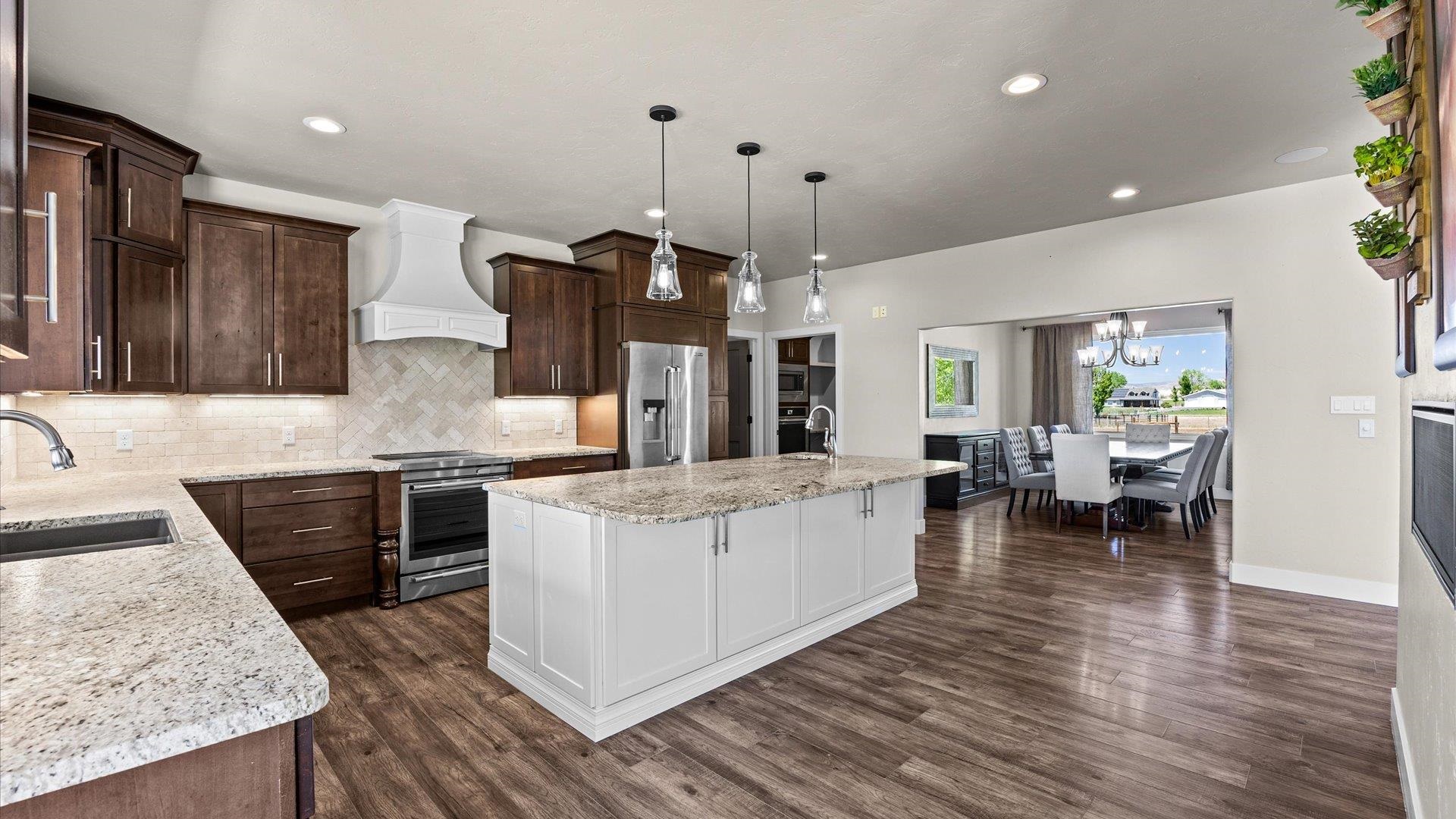 2041 J J 1/2 Road Fruita, CO 81521 - Photo 8 of 42 a kitchen with stainless steel appliances kitchen island granite countertop a stove a sink a refrigerator and chairs with wooden floor