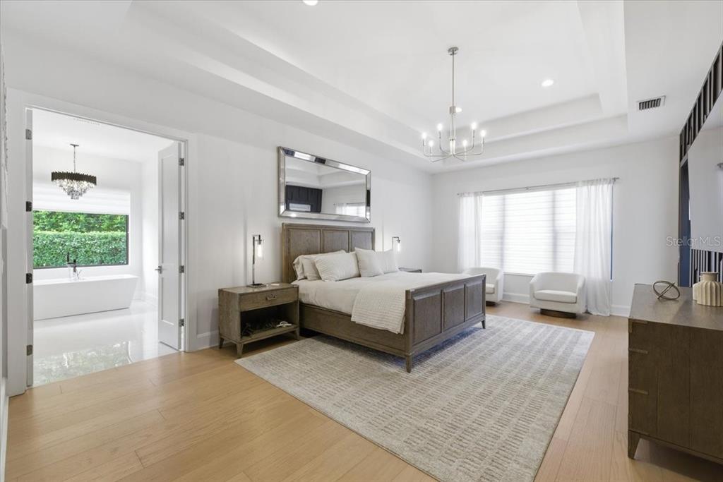 2829 Coastal Range Way Lutz, FL 33559 - Photo 32 of 64 a spacious bedroom with a bed and a chandelier