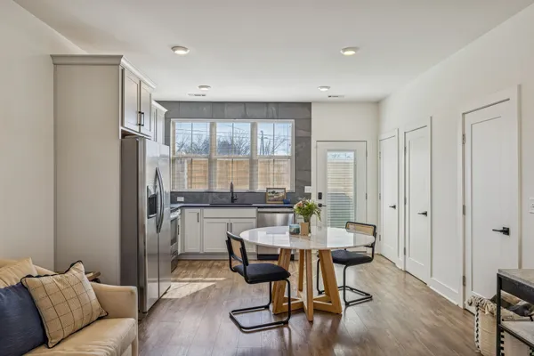 a kitchen with stainless steel appliances granite countertop a stove a refrigerator a kitchen island a dining table and chairs with wooden floor