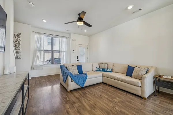 a kitchen with stainless steel appliances a stove a sink a microwave a refrigerator white cabinets and wooden floor