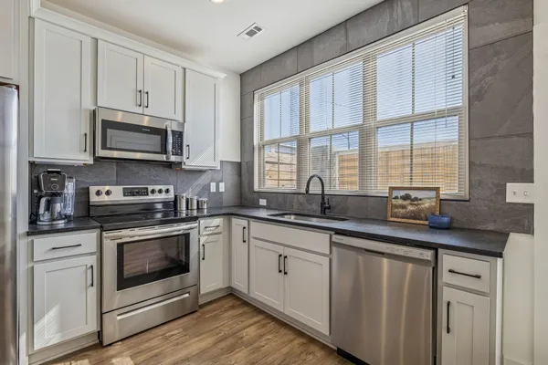 a kitchen with stainless steel appliances granite countertop a sink a stove a cabinets and a window